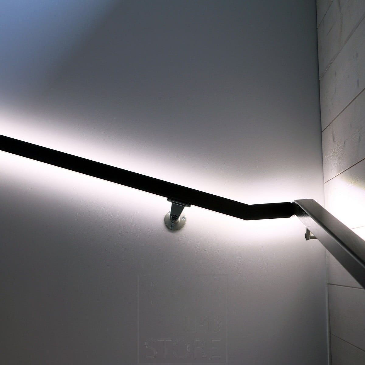 A wall-facing led strip on a handrail, allowing the light to illuminate the wall with indirect, soft light.